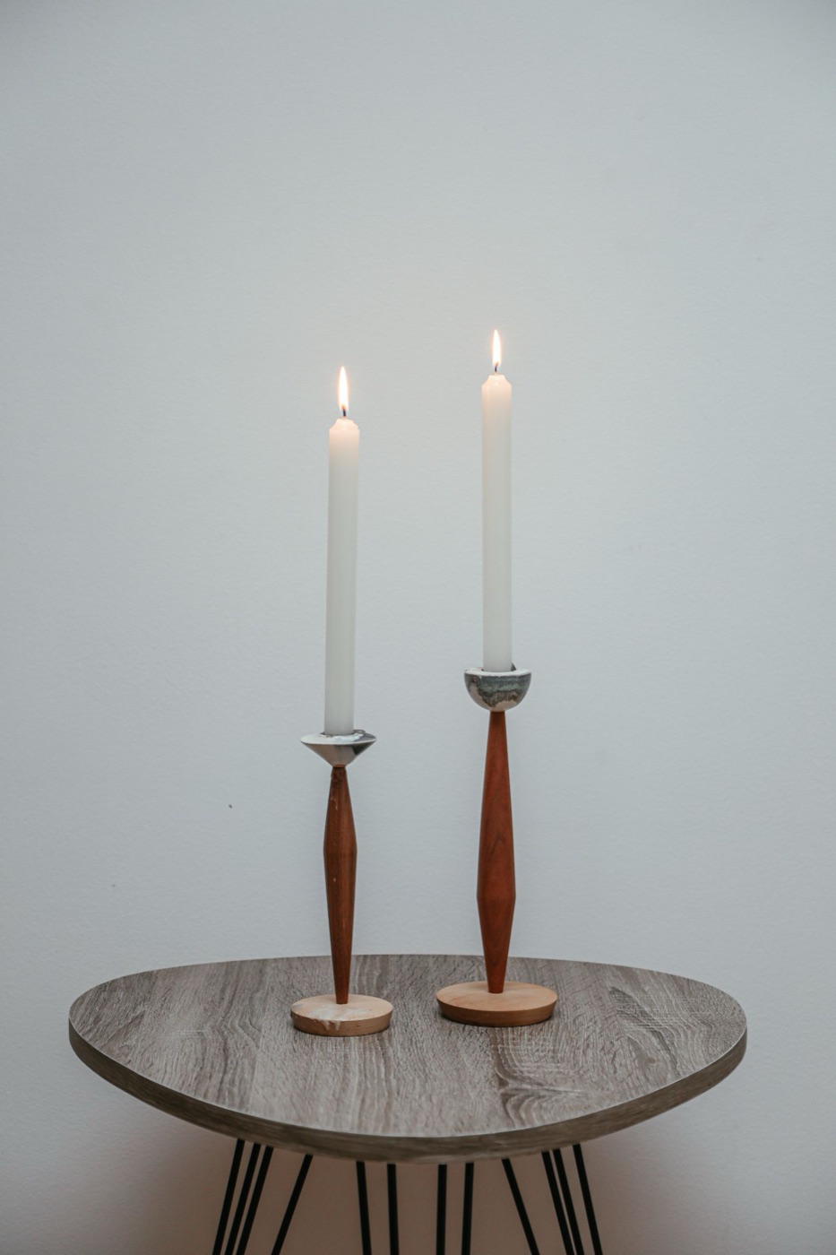 A turned wooden candle stand holding a lit candle on a tray